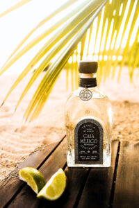 Bottle of Casa Mexico Cristalino Tequila with limes by the Beach